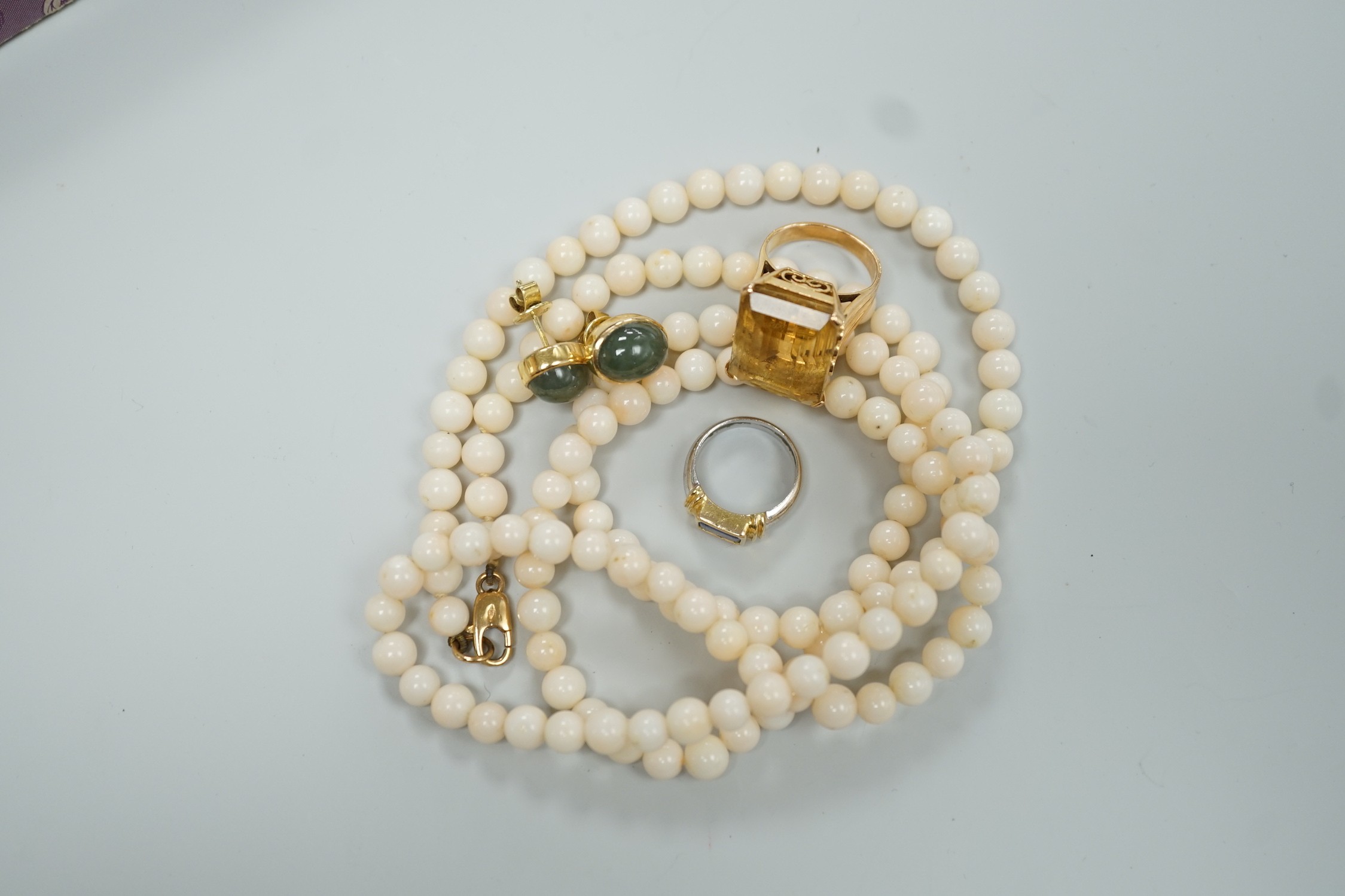 A modern 18k and single stone sapphire set child's ring, size G, a yellow metal and citrine set ring, size J, a pair of 585 and green cabochon set ear studs and a simulated coral bead necklace.